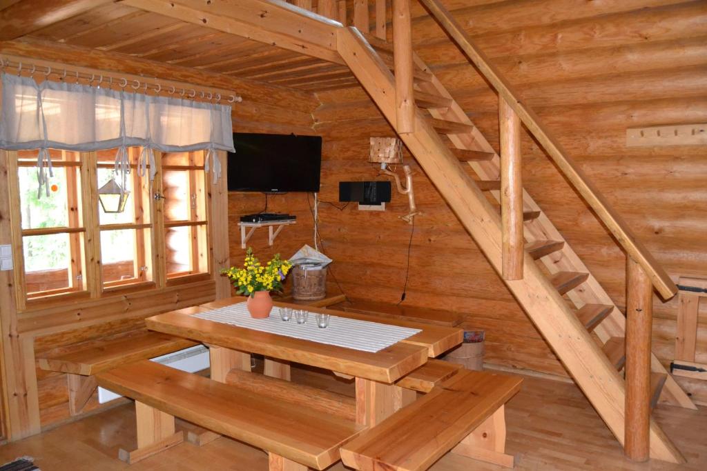 ein Holzzimmer mit einem Tisch und einer Treppe in der Unterkunft Forest Cottage in Säkylä