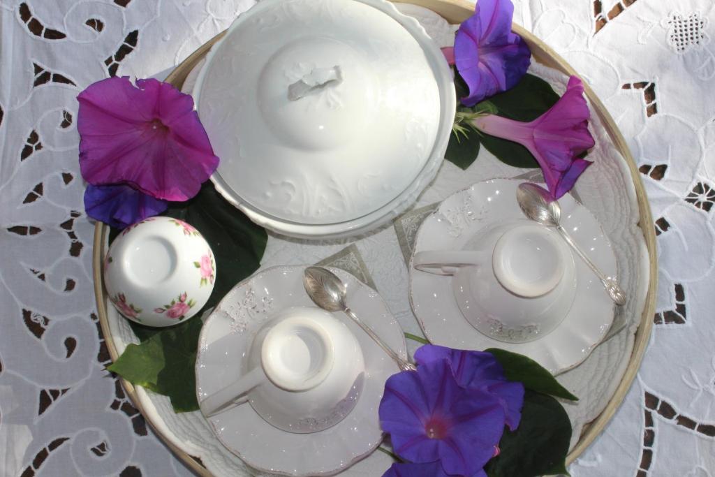 a table topped with white plates and purple flowers at Chambre d'hôtes l'ipomée in Gémenos