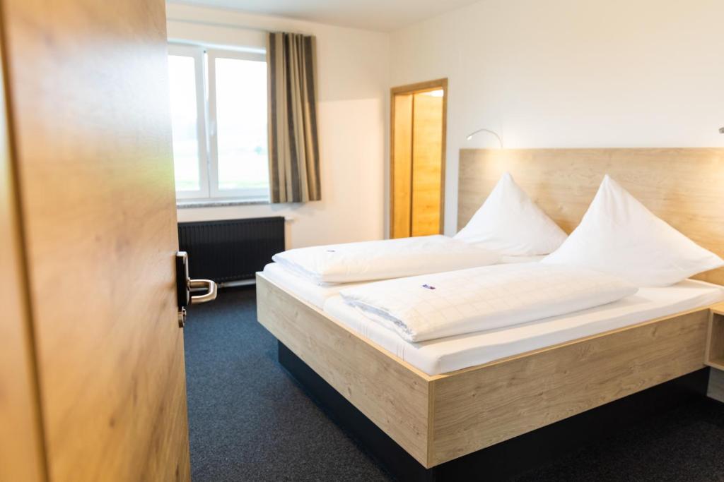 1 dormitorio con 1 cama grande con sábanas blancas en Gasthof Linde - Hotel Blum, en Unterroth