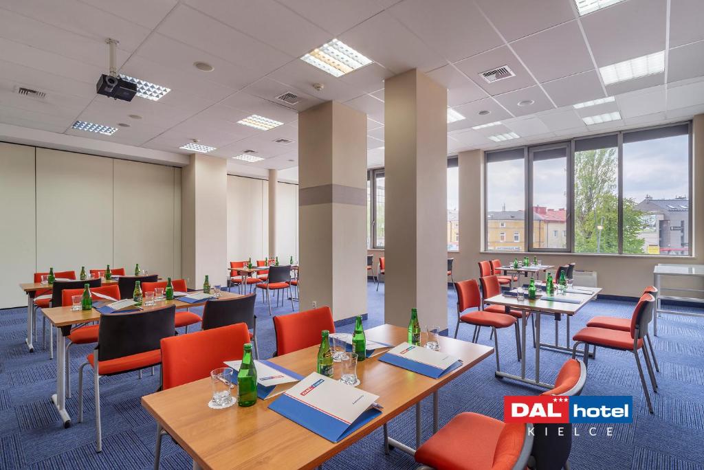 Large conference room with multiple tables, orange chairs, bottled water, notepads, daylight city windows.