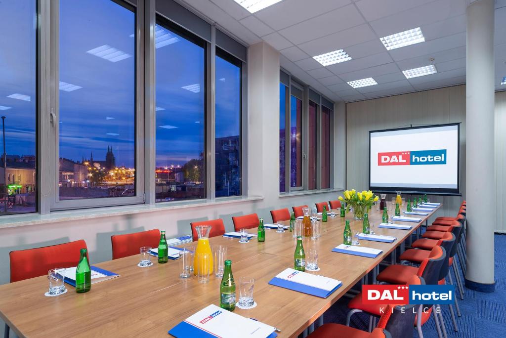 Evening boardroom with long wooden table, pitchers, water bottles, tulip centerpiece, city lights outside.