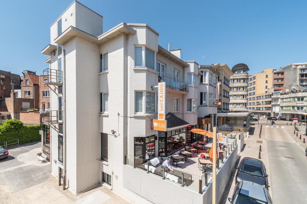 an apartment building with a balcony with a restaurant at Hotel Cajou in De Panne