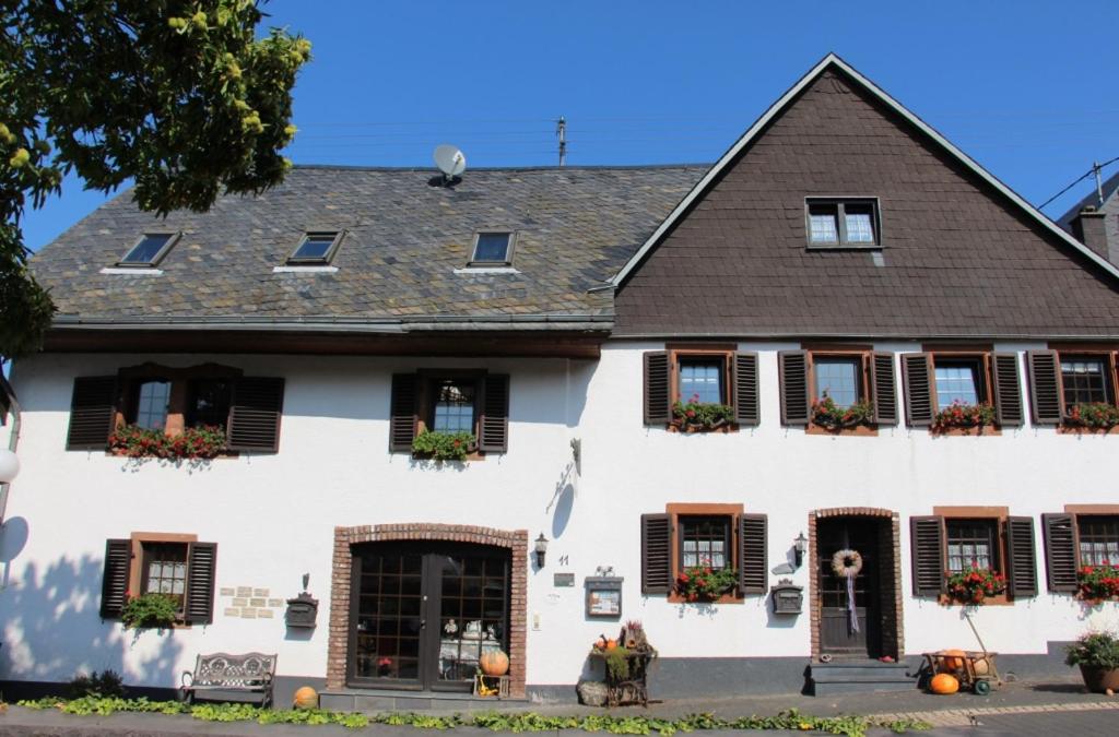 a white house with black shuttered windows at Ferienwohnung Flämisches Weinhaus in Wintrich