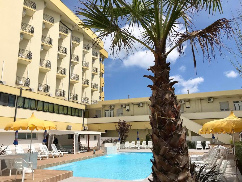 uma palmeira em frente a um hotel com piscina em Hotel Montmartre em Rimini