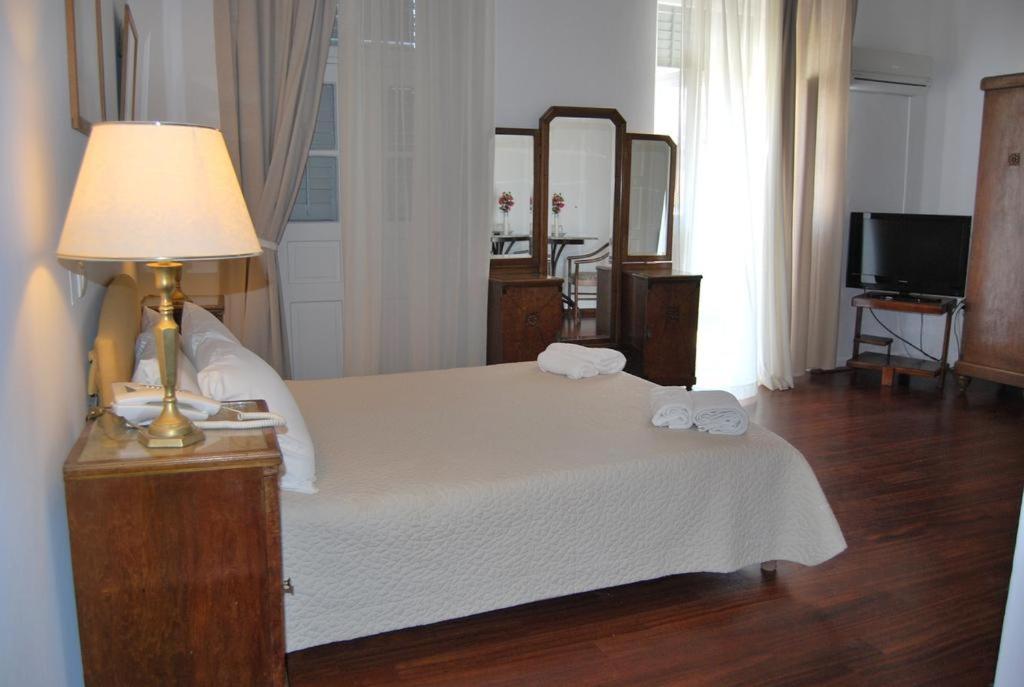 a bedroom with a bed with a lamp and a mirror at Hotel Miranda in Hydra