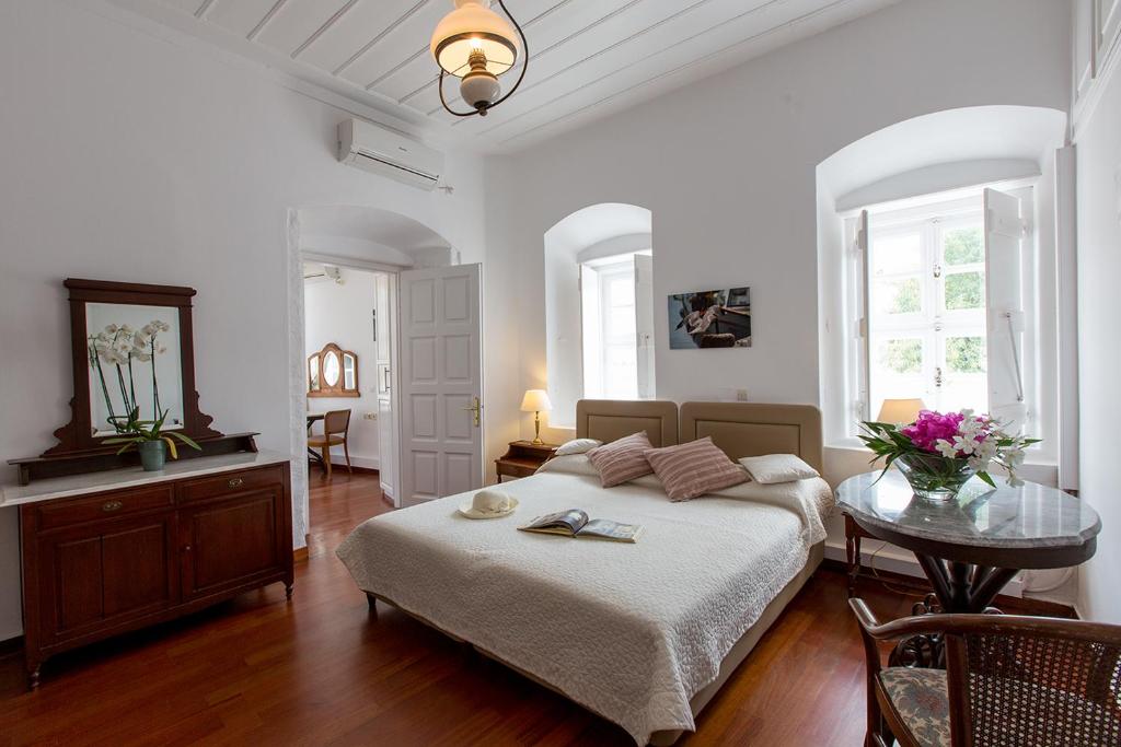 a white bedroom with a bed and a table at Hotel Miranda in Hydra
