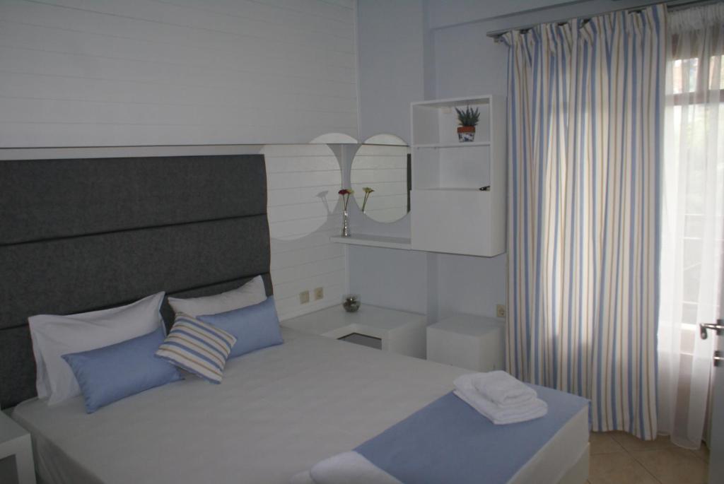 a bedroom with a bed with blue pillows and a window at Nostos Rooms Ammouliani in Ammouliani