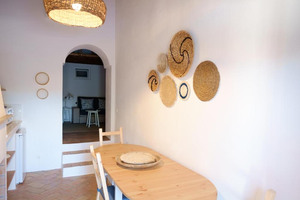 ein Esszimmer mit einem Tisch und Strohhüten an der Wand in der Unterkunft Casas de Mértola in Mértola