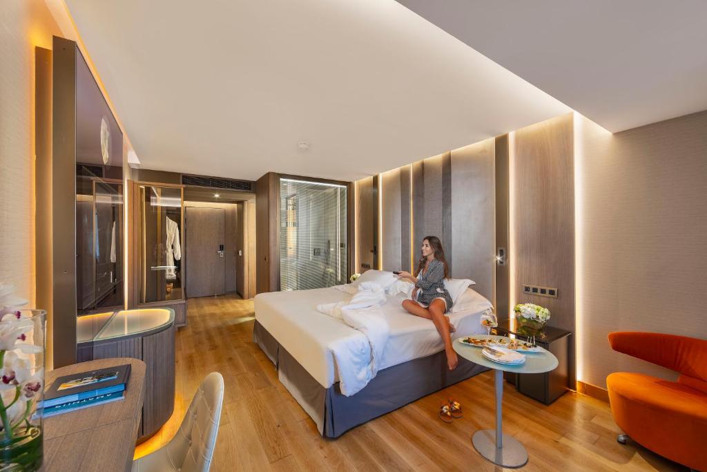 a woman sitting on a bed in a hotel room at Amathus Beach Hotel Limassol in Limassol