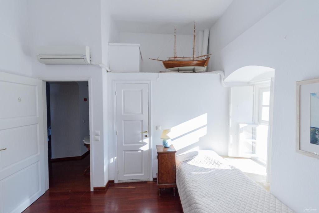 a bedroom with white walls and a bed and a window at Hotel Miranda in Hydra