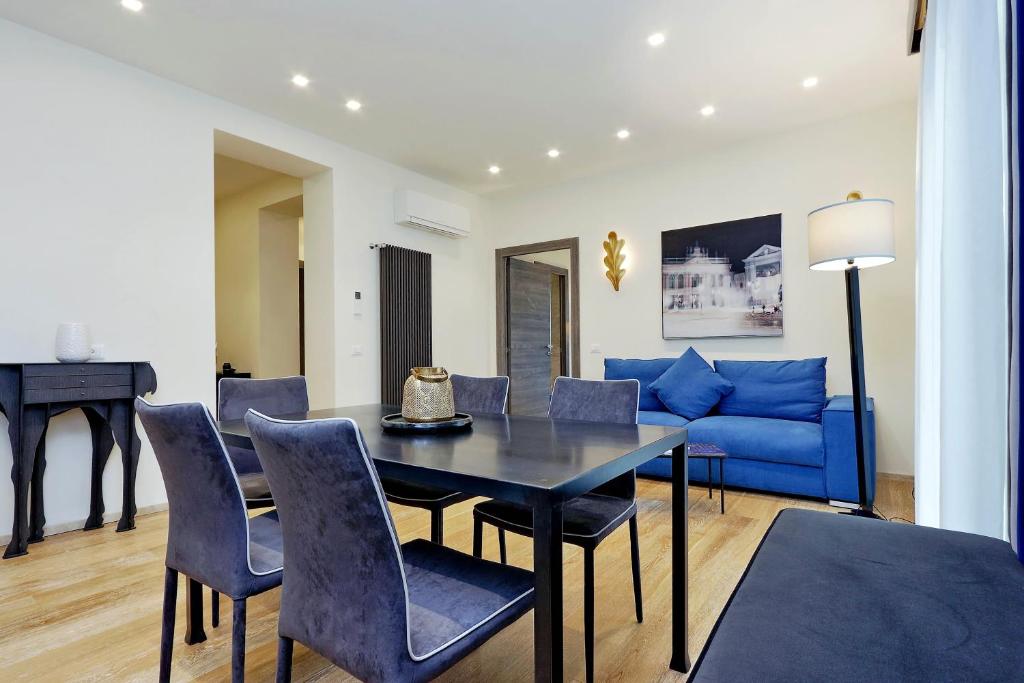 un soggiorno con divano blu, tavolo e sedie di Houses&HousesVEDOROMA a Roma