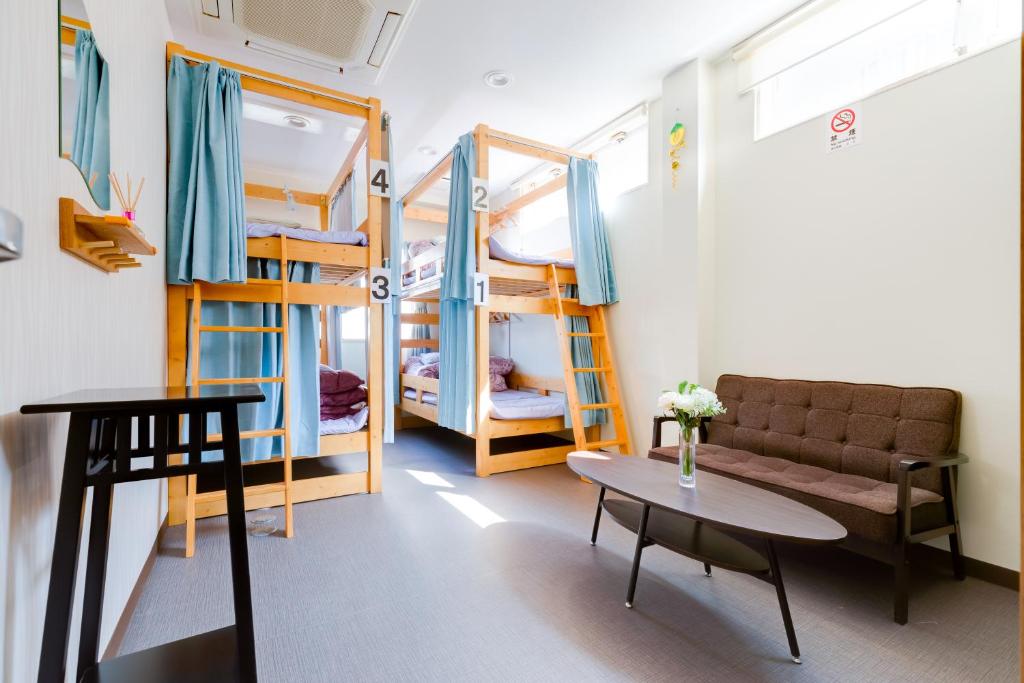 泉佐野市にあるABCゲストハウス（1階）の二段ベッド、ソファ、テーブルが備わる客室です。