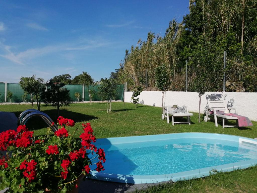 a backyard with a swimming pool and red flowers at Casa Salitre in Boiro
