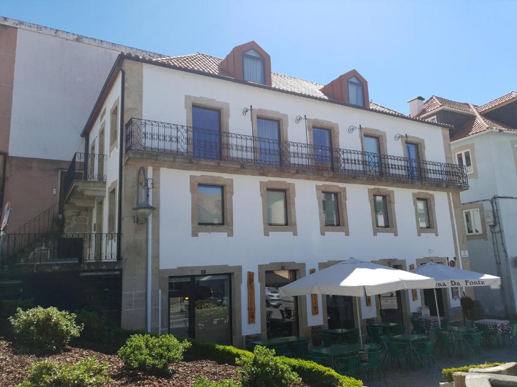 un grand bâtiment blanc avec des tables et un parasol dans l'établissement Alojamento 4 Bicas, à Seia