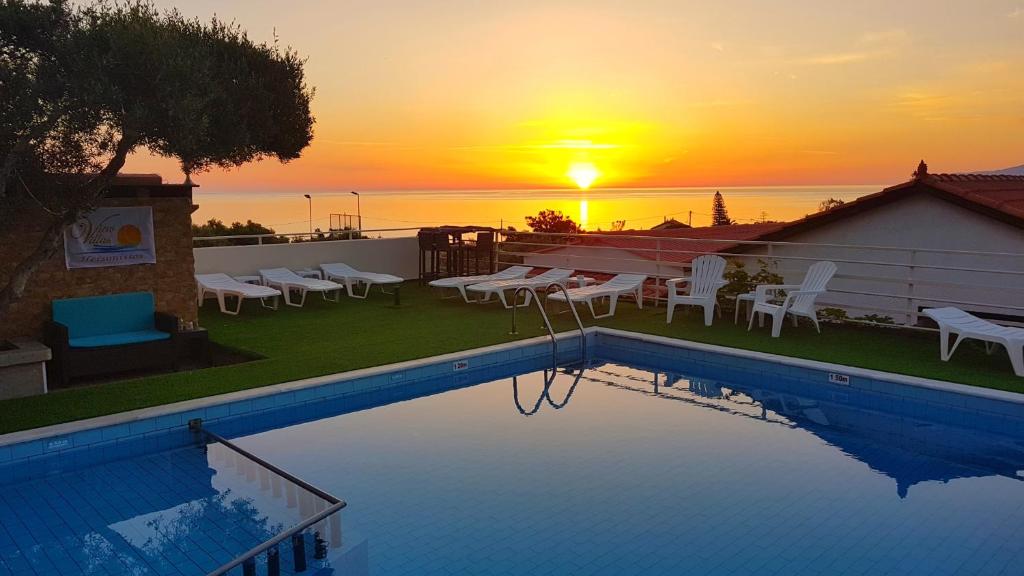 a swimming pool with a sunset in the background at View Villas in Hersonissos