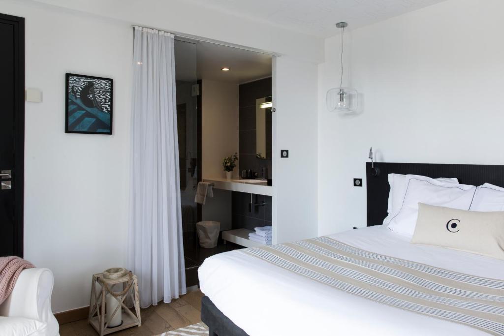 a bedroom with a white bed and a bathroom at Castel Beau Site in Perros-Guirec