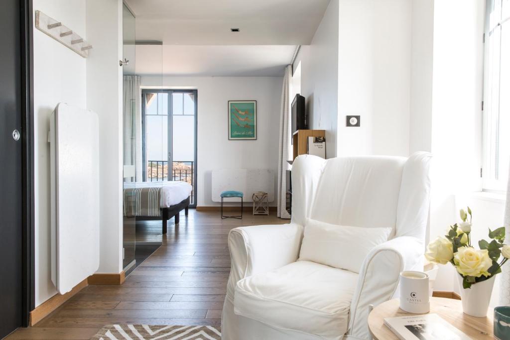 a white living room with a white chair and a table at Castel Beau Site in Perros-Guirec