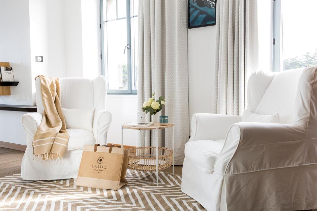 a living room with two white chairs and a table at Castel Beau Site in Perros-Guirec