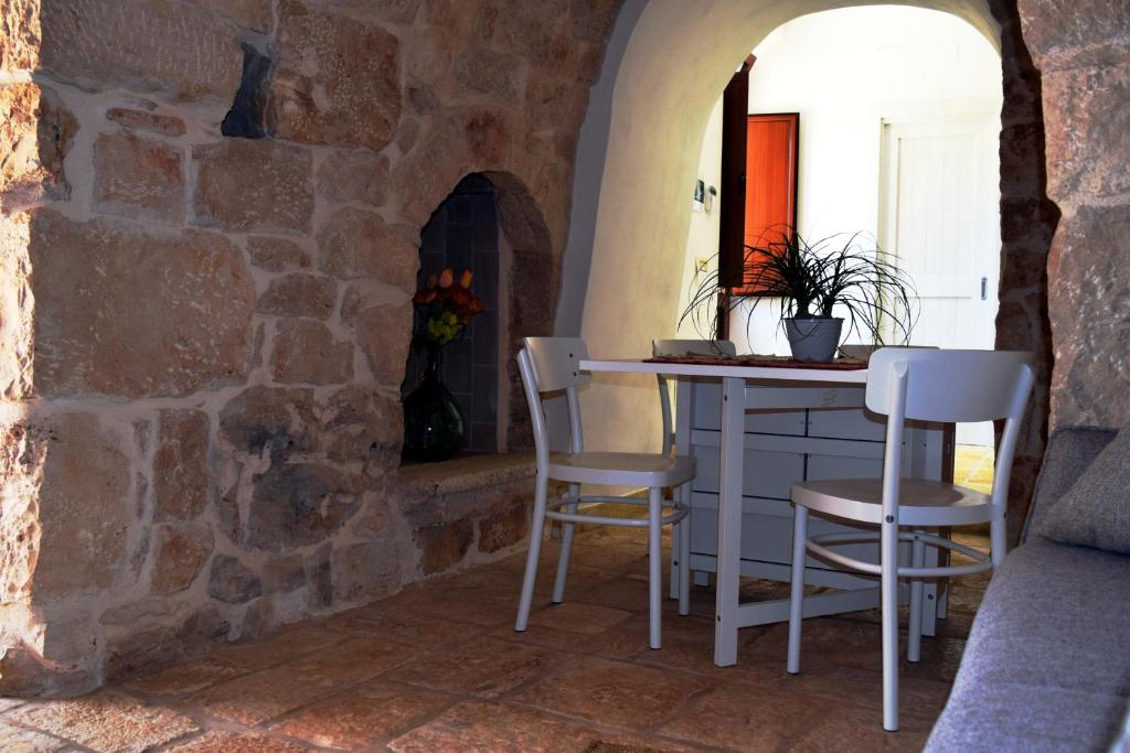 Habitación con mesa y sillas en una pared de piedra. en Dimore Storiche - Ulivo di Aldo, en Martina Franca