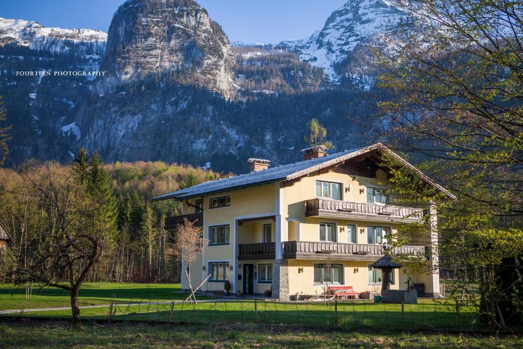 ein großes Haus mit einem Berg im Hintergrund in der Unterkunft Landhaus Lilly in Obertraun