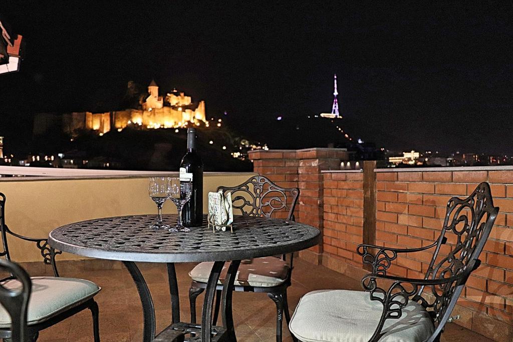a table with wine glasses on a balcony at night at Penthouse Apartment 401 in Tbilisi City