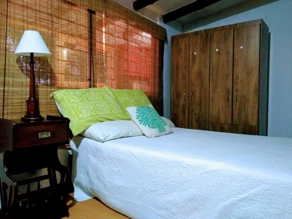 sypialnia z białym łóżkiem i stołem z lampką w obiekcie Finca Colibrí Zafiro, Altos del Rosario w mieście Cali