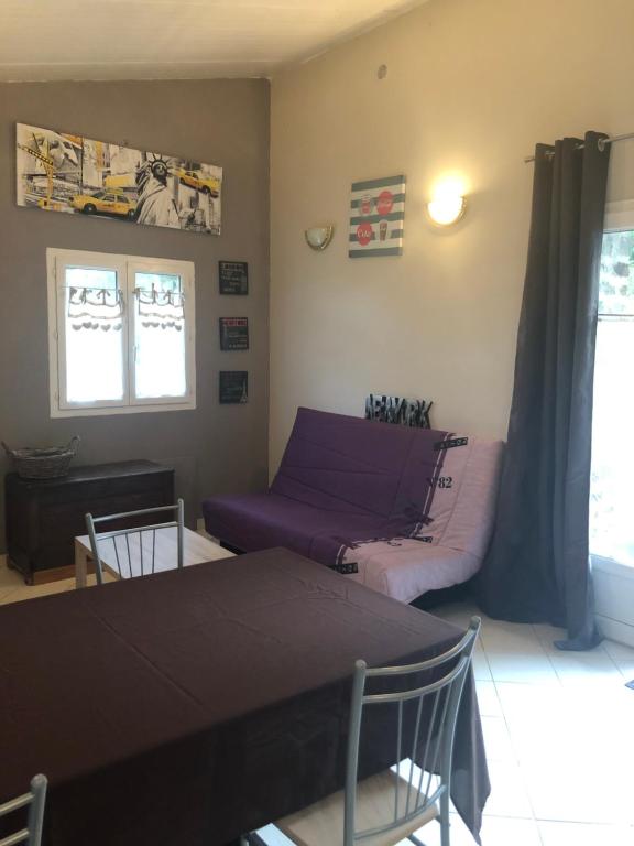 a living room with a table and a purple couch at Maisonnette plein pied - 2km de la mer in Agon-Coutainville
