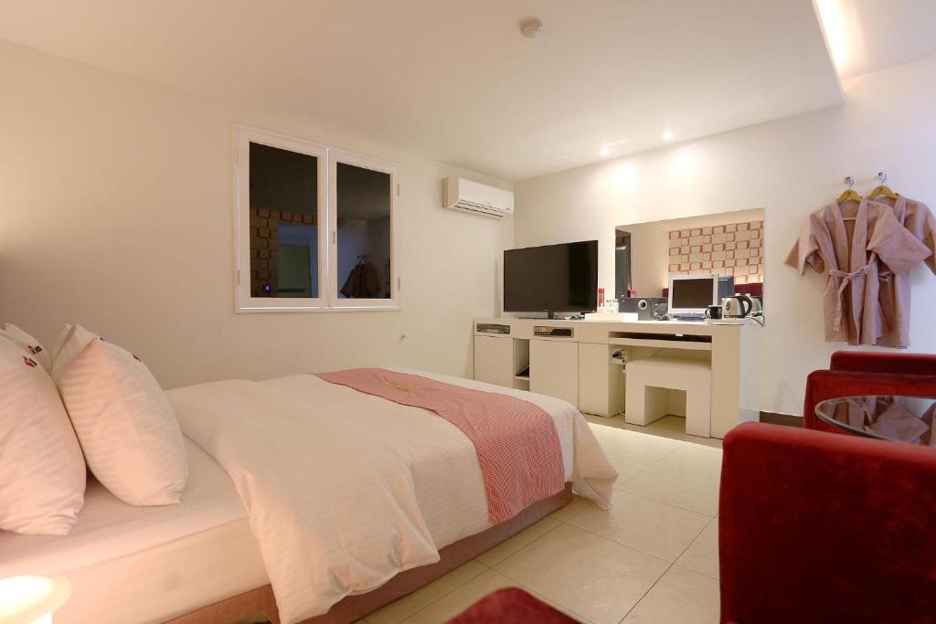 a white bedroom with a bed and a desk at Q Hotel in Paju