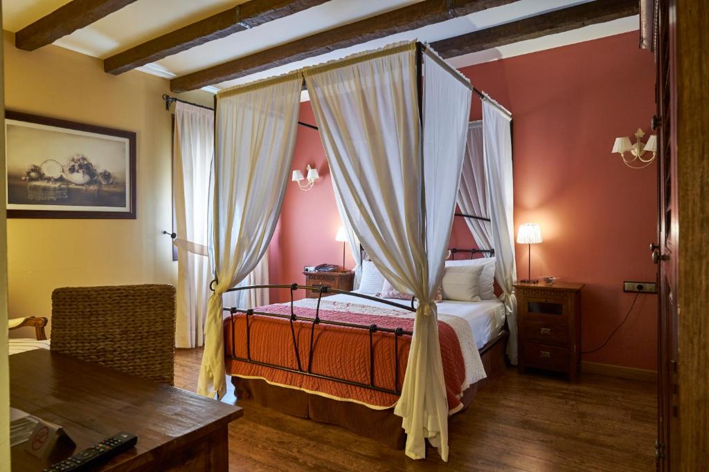 Un dormitorio con una cama con dosel y un escritorio. en Casona De Torres, en Mondéjar