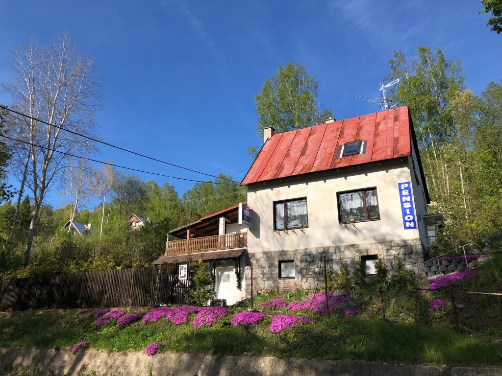 ein Haus mit rotem Dach und lila Blumen in der Unterkunft Penzion Tereza in Kraslice