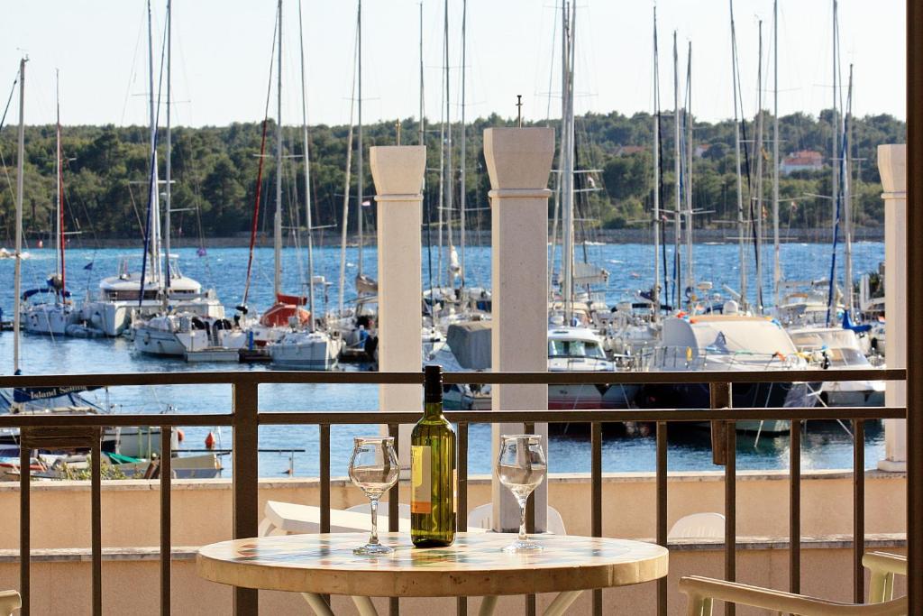 a bottle of wine on a table on a balcony with boats at VILLA V&D in Milna