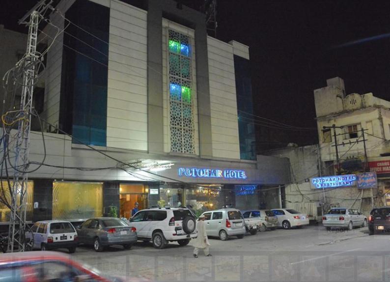 un grande edificio con auto parcheggiate in un parcheggio di Potohar Hotel a Rawalpindi