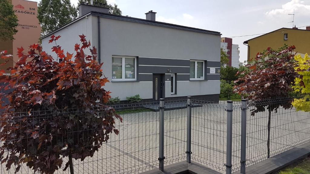 Biały dom za płotem w obiekcie Apartament Angelo w mieście Sosnowiec