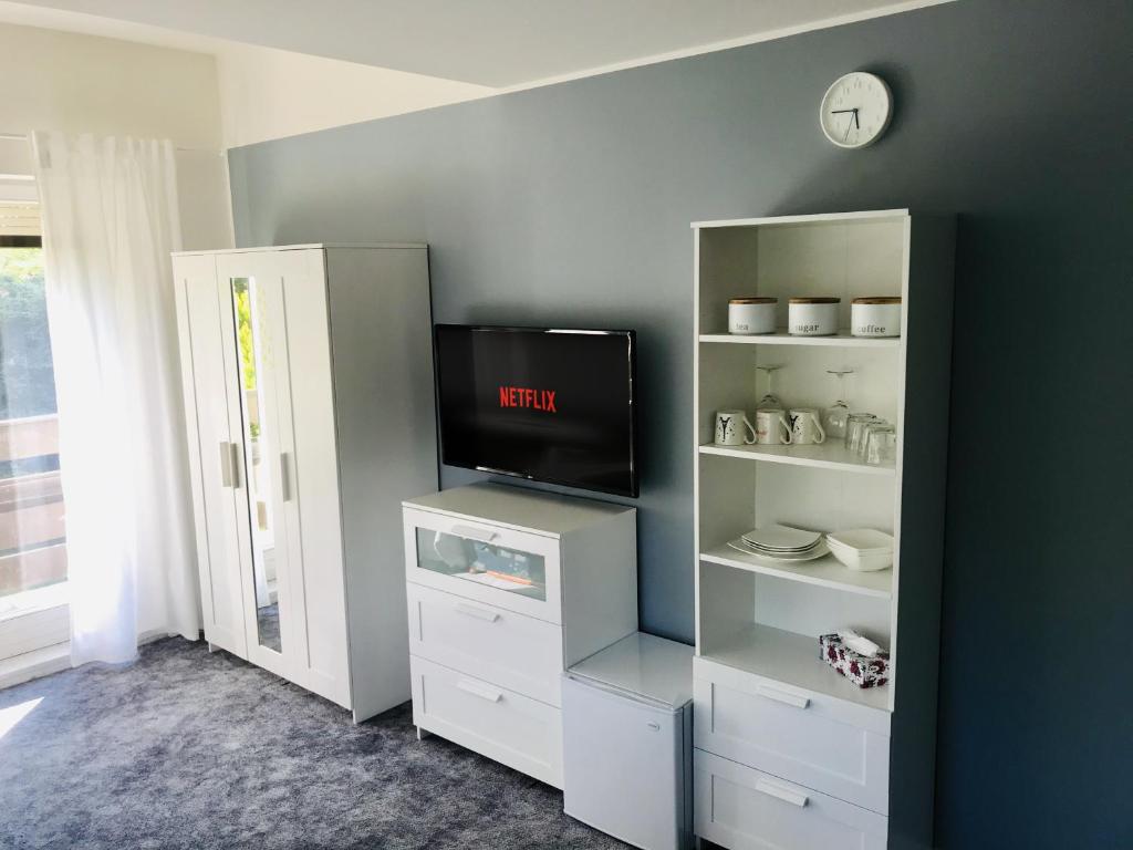 a living room with a tv and white shelves at Zakątek Podolany in Poznań