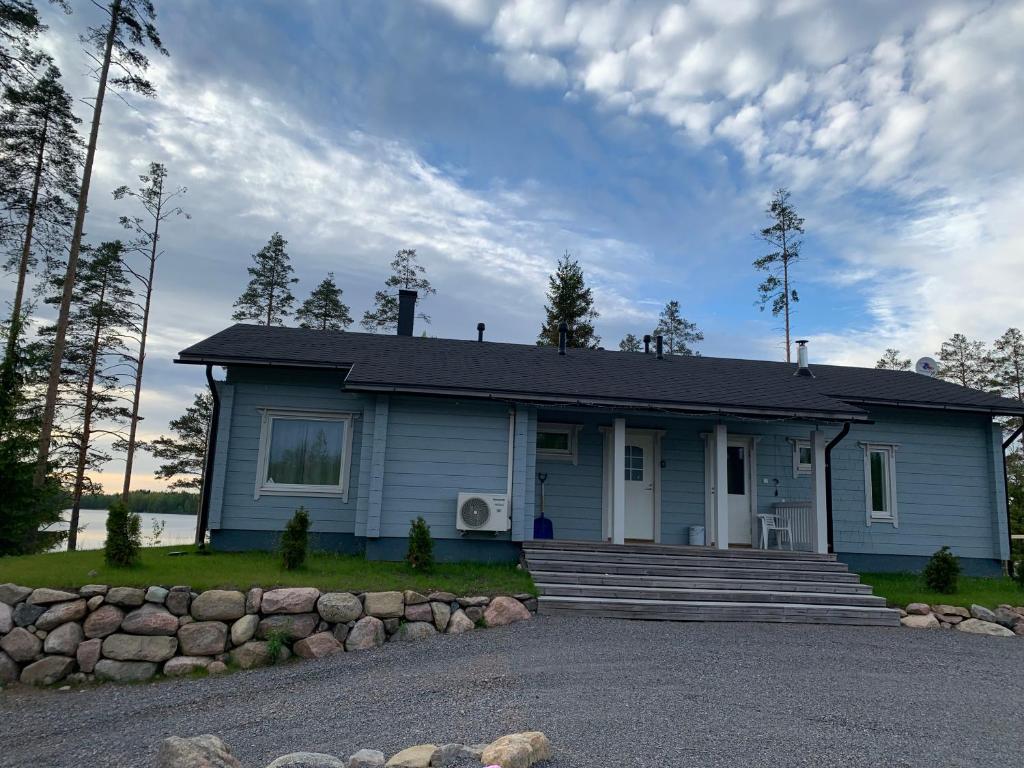 a small blue house with a stone wall at VITA Ruokolahti 1-2 in Ruokolahti