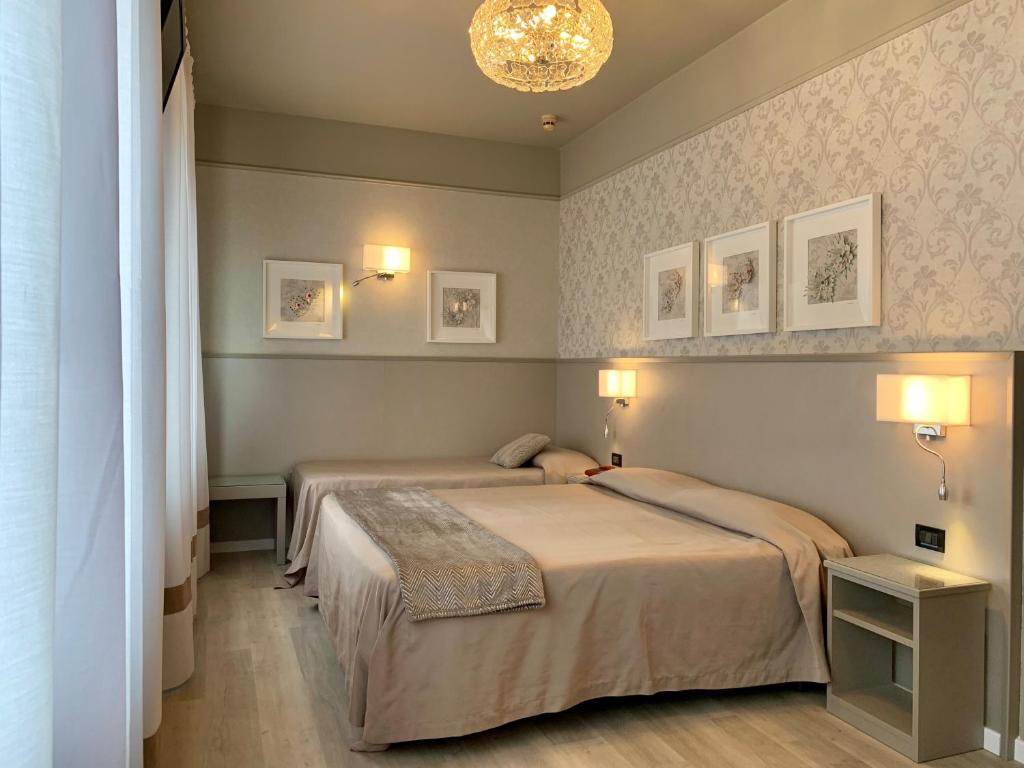 a bedroom with two beds and a chandelier at Hotel La Pace in San Mauro Torinese