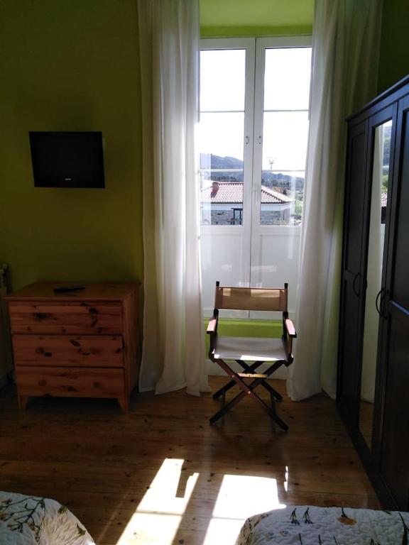 a bedroom with a chair and a dresser and a window at La Clinica in Ballota