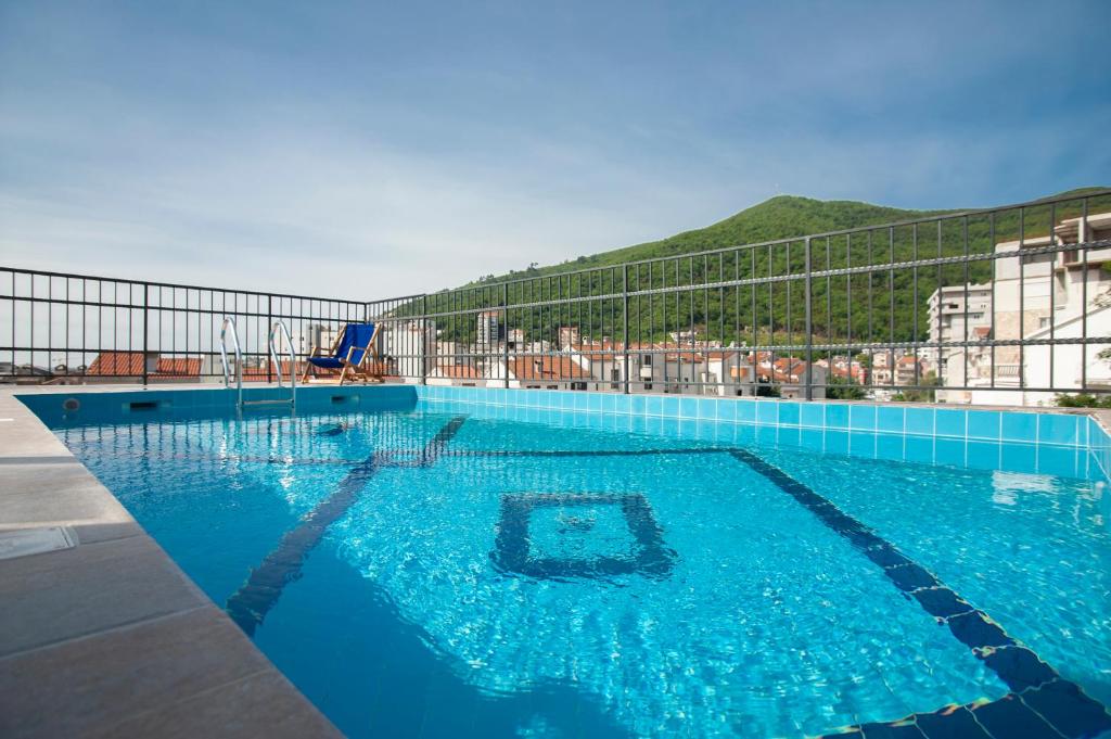 a large blue swimming pool with a mountain in the background at Hotel Twelve by Aycon in Budva