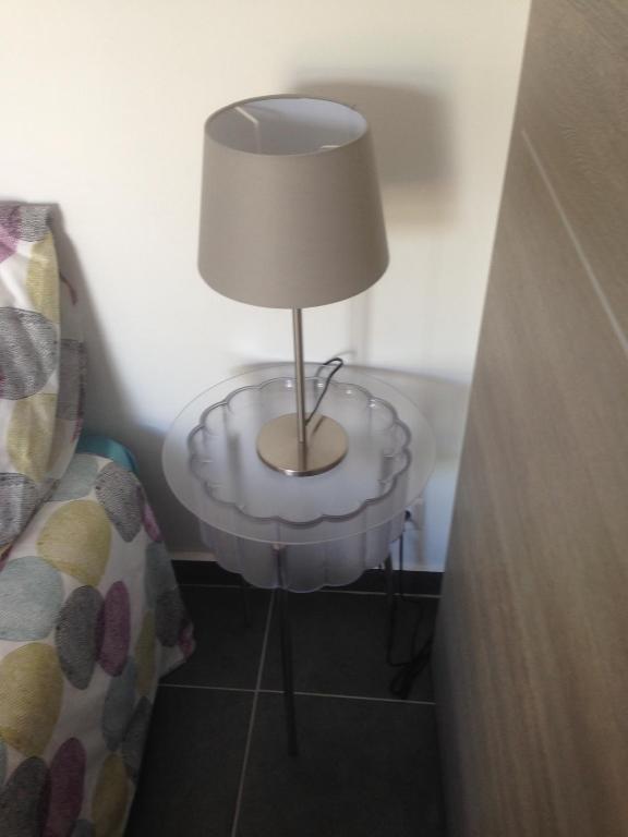 a lamp on a glass table next to a bed at Gîte Polema in Marseille