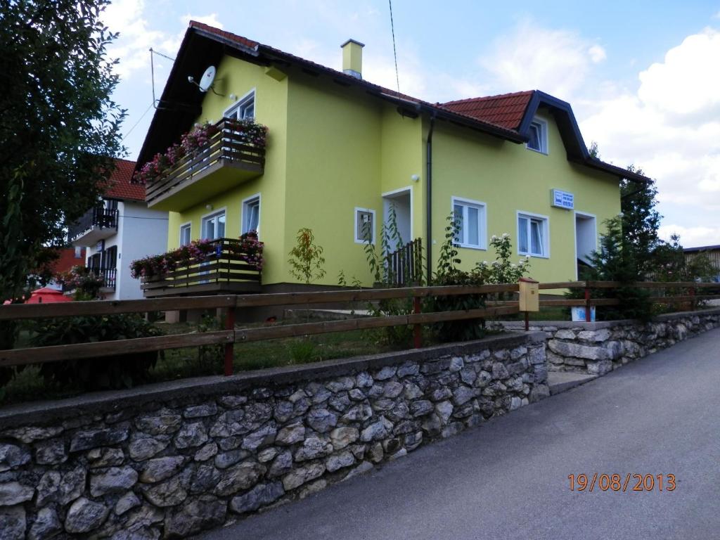 a yellow house with balconies on a stone wall at Rooms Jure Sabljak in Grabovac