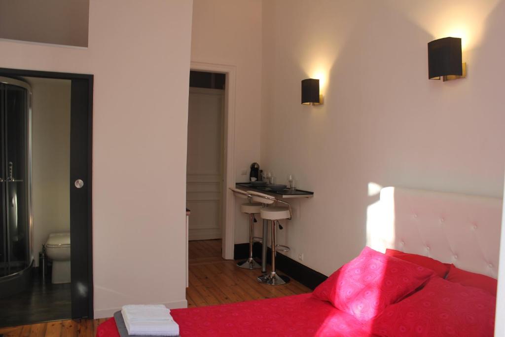 a bedroom with a red bed and a sink at Les Cariatides in Lille
