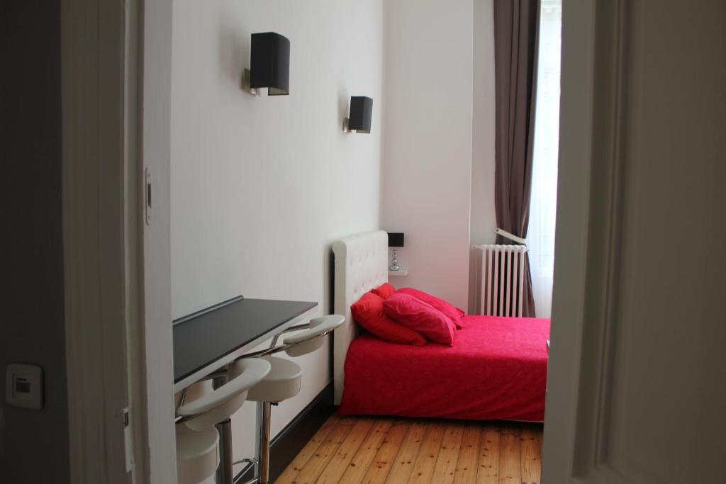 a bedroom with a red bed and a flat screen tv at Les Cariatides in Lille