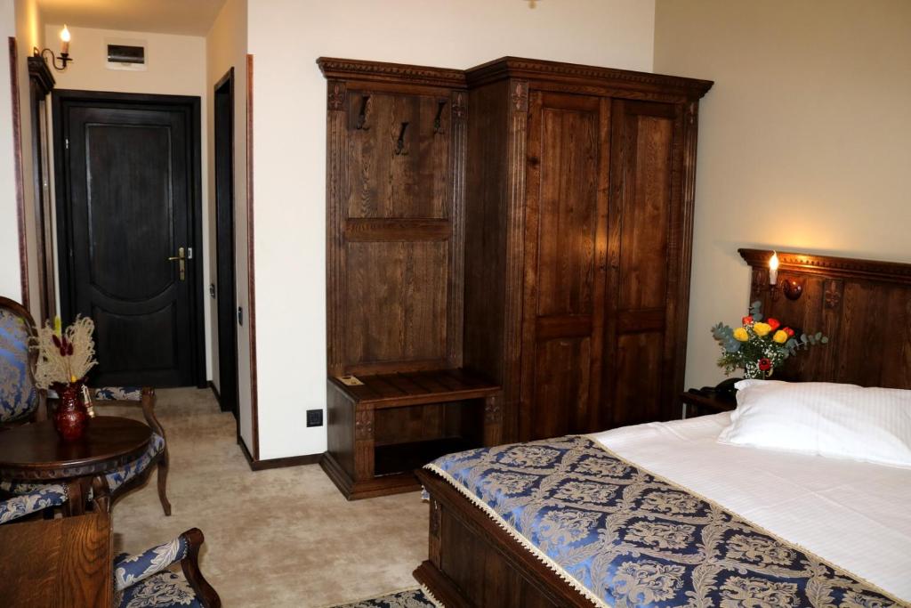 a bedroom with a bed and a wooden cabinet at Castel Transilvania in Baia Mare
