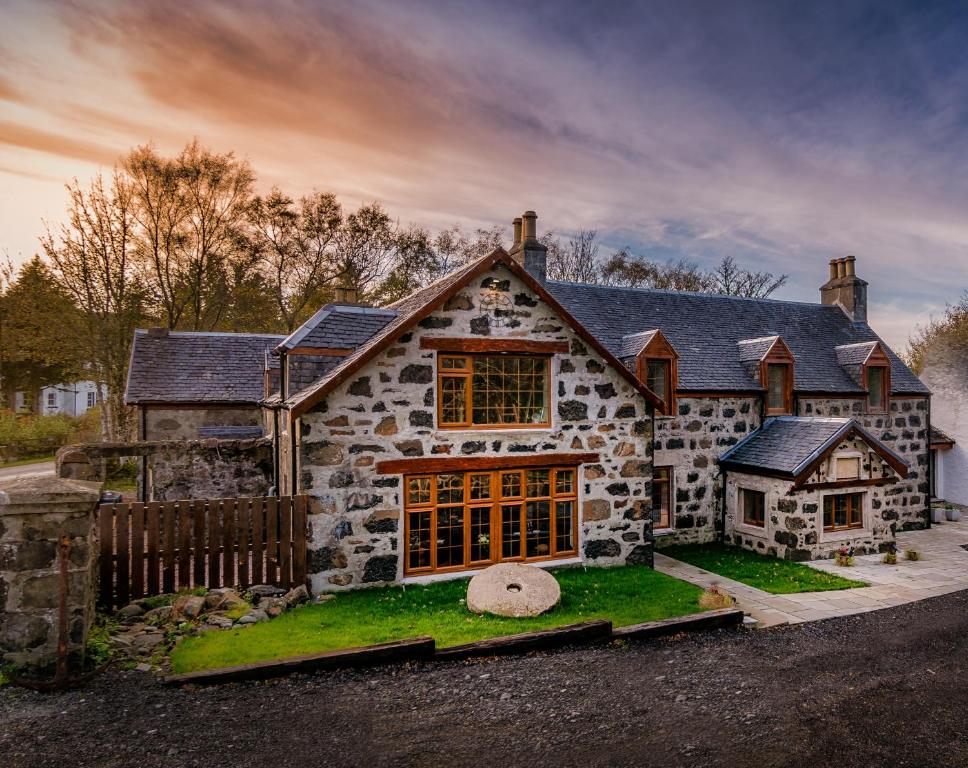 a large stone house with a fence in front of it at Edinbane Lodge in Edinbain