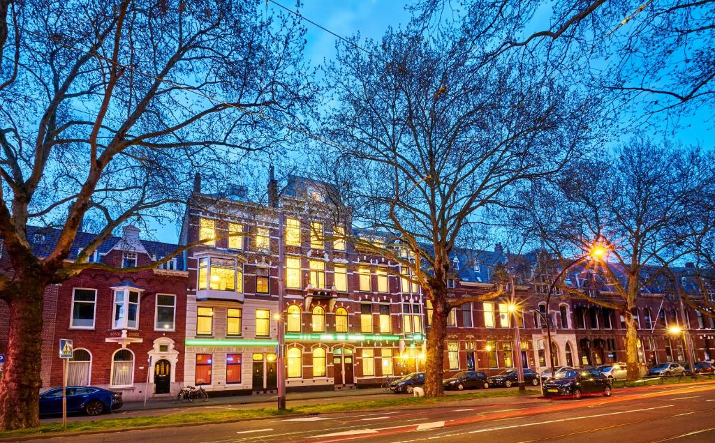 un bâtiment éclairé dans une rue de la ville la nuit dans l'établissement Hotel Van Walsum, à Rotterdam