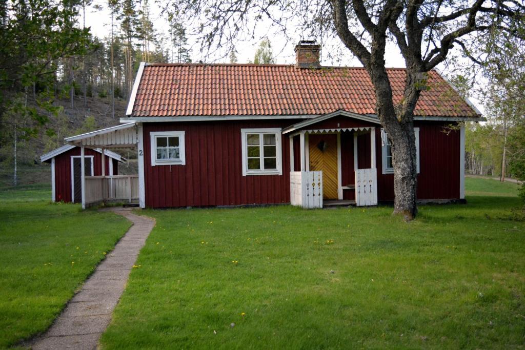 una casa rossa con un albero nel cortile di Högerödja a Hultsfred