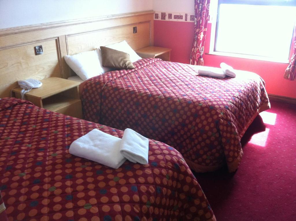 two beds in a hotel room with towels on them at Pier House Bed & Breakfast in Inis Mor