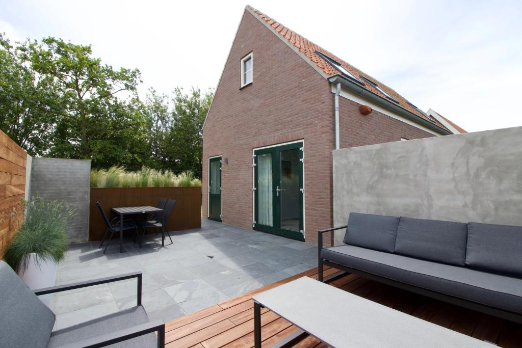 a patio with a couch and a table at Zeeuws Huisje in Serooskerke