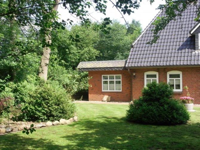 a red brick house with a tree and a yard at Hof Glücksburg in Dörpum