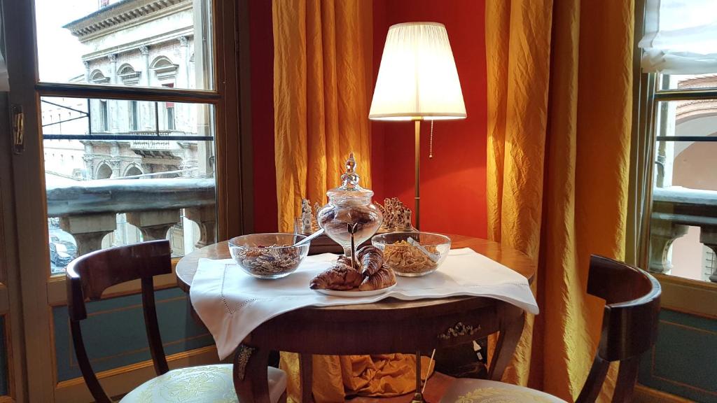un tavolo con ciotole di cibo sopra davanti a una finestra di Palazzo di Alcina - Residenza d'Epoca - Luxury- a Bologna